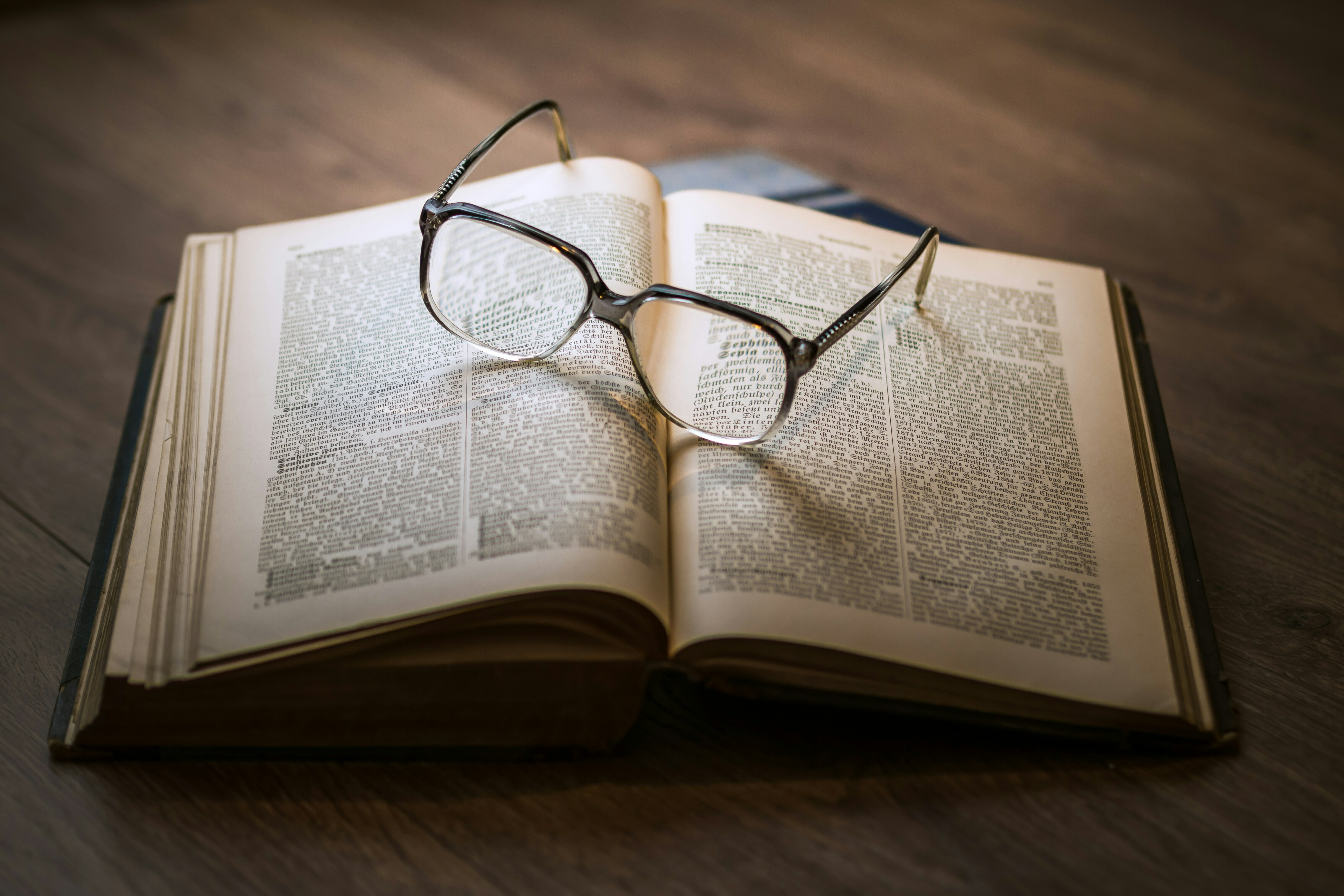 Ein aufgeschlagenes Buch mit einer Brille, welche auf diesem liegt